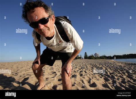 50 Year Old Man Leaning Forward Towards The Camera On A Beach Blue Sky