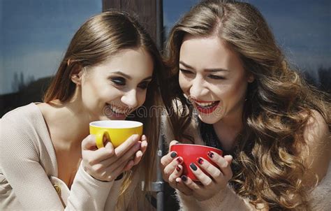 Two Young Pretty Woman Laughing Outdoors And Drinking Coffee Li Stock