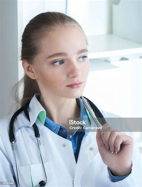 Retrato De Closeup De Joven Pensativo Doctor En Uniforme Blanco Sentado