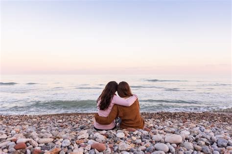 premium photo couple of lesbian girls sitting on the beach watching and enjoying a beautiful