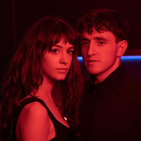 A Man And Woman Standing Next To Each Other In A Dark Room With Neon Lights
