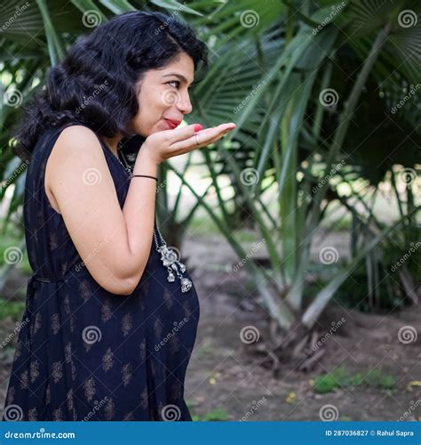 a pregnant indian lady poses for outdoor pregnancy shoot and hands on belly indian pregnant