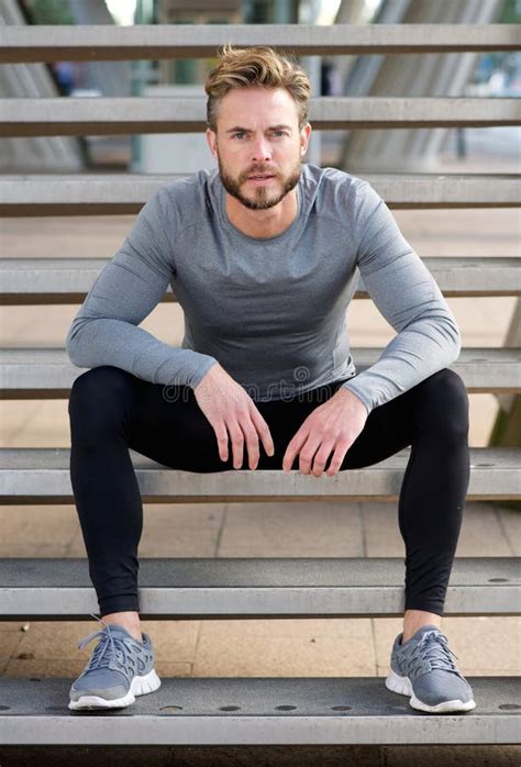 Handsome Fit Man With Beard Sitting On Steps Outside Stock Photo