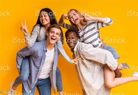 Two International Student Couples Having Fun Over Yellow Background