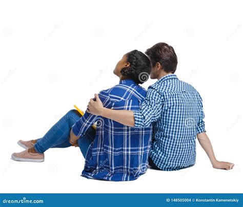 Back View Of A Multiethnic Young Couple Sitting On The Ground And