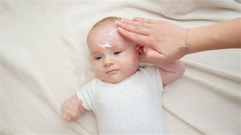 Closeup Of Mother Applying Moisturizing Cream On Her Little Baby Face