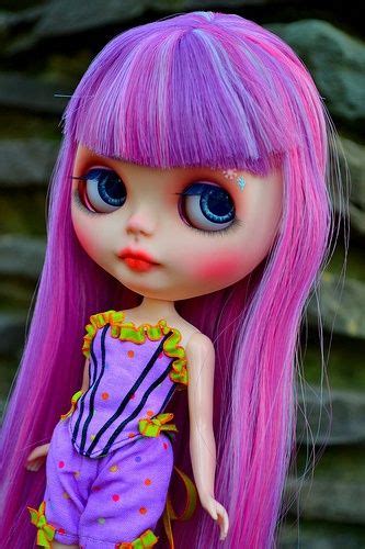 a close up of a doll with pink hair and blue eyes wearing a purple outfit