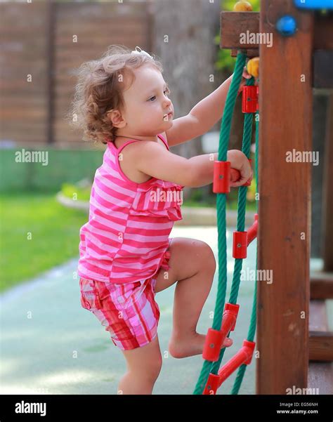 Small Girl Child Climbing Up On Children Activity Ladder Outdoors Stock