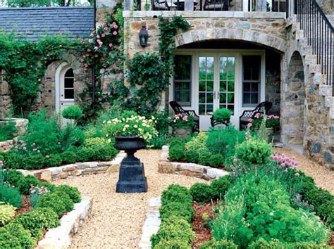 A Stone House With Lots Of Plants And Flowers In The Front Yard Along