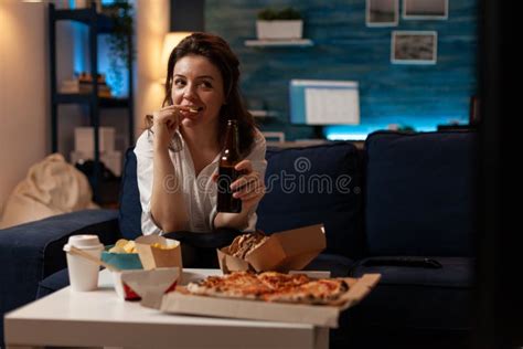 Woman Relaxing On Sofa Watching Television While Drinking Craft Beer