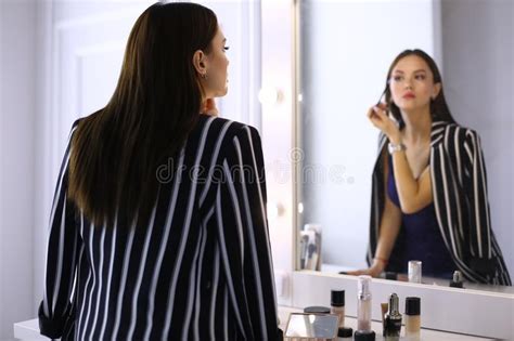 Reflection Of Young Beautiful Woman Applying Her Make Up Looking In A