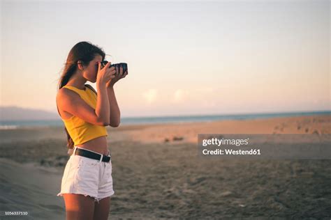 Teenage Girl Taking Photos With Camera On The Beach At Sunset Photo