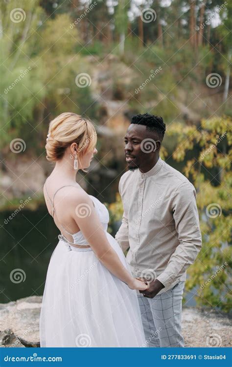 Happy Interracial Couple Newlyweds Stands On Rock And Holds Each Other