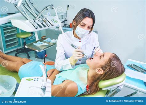 Girl Sitting At Dental Chair With Open Mouth During Oral Check Up While