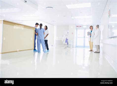 Doctors And Nurses Talking By Nurses Station In Hospital Stock Photo