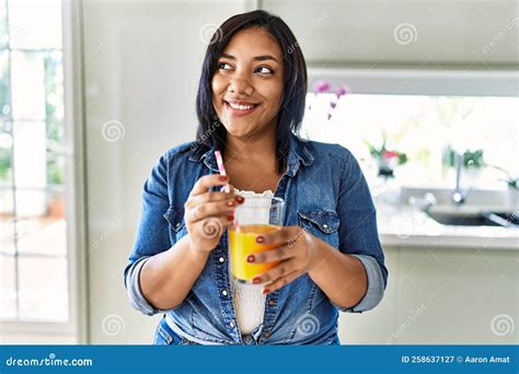 Hispanic Brunette Woman Drinking A Glass Of Fresh Orange Juice At The
