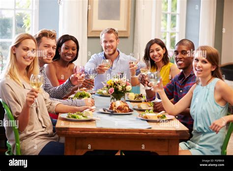 Friends At Home Sitting Around Table For Dinner Party Stock Photo Alamy
