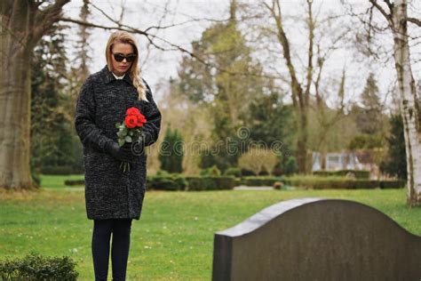 Woman Grieving At Cemetery Holding Flowers Stock Image Image Of