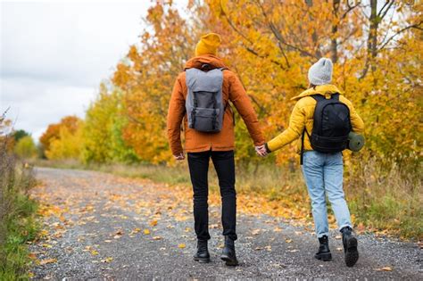 premium photo back view of couple hikers with backpacks hiking in autumn forest