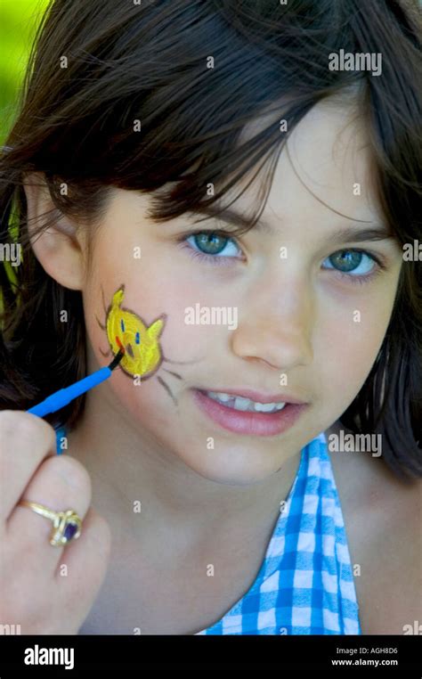 7 Year Old Girl Has Image Of A Yellow Cat Painted On Her Face Stock