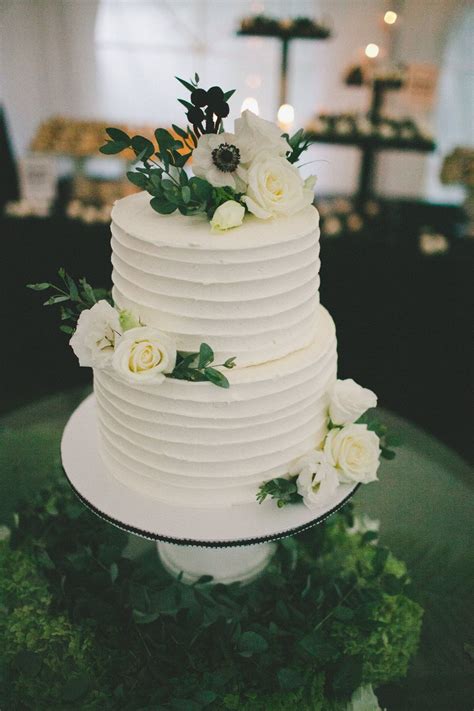 simple two tier wedding cake covered in real blossoms and greenery the cake is chocola