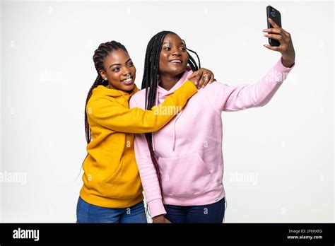 Two African American Girls Taking Selfie Photos With Her Cell Phone On Gray Background Stock