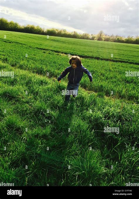 Boy Running Through Fields Of Grass Stock Photo Alamy