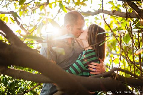 A Man And Woman Are Kissing In The Tree Branches With Sunlight Streaming Through Them On Their