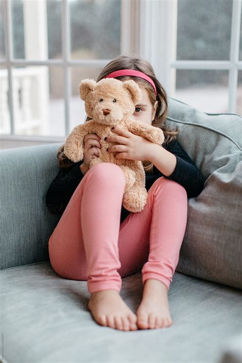 Cute Young Girl Sitting On A Big Chair Playing With Her Teddy Bear By