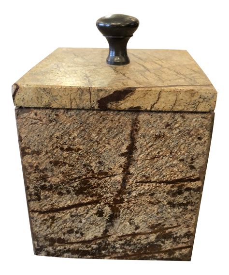 A Stone Box With A Black Handle On The Top Is Shown In Front Of A White