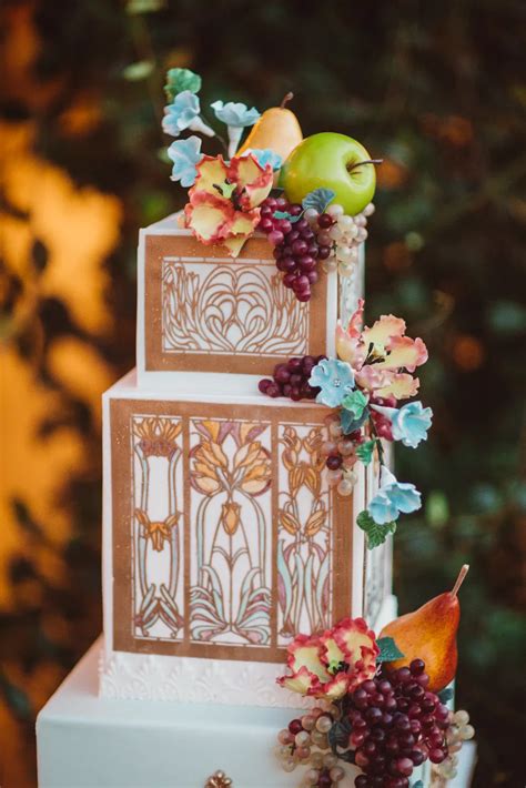 A Three Tiered Cake With Fruit And Flowers On Top Is Displayed In Front
