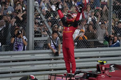 A Man Standing On Top Of A Red Race Car In Front Of A Large Crowd