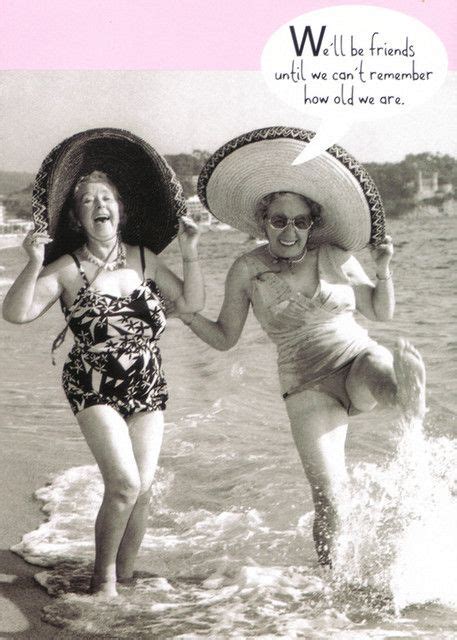 Two Girls In Swimsuits And Hats Running Into The Water With An Umbrella Over Their Heads