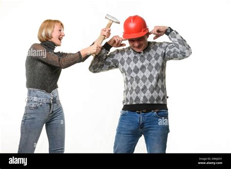 the wife screams and hits her husband on the head with a hammer the husband is wearing a helmet