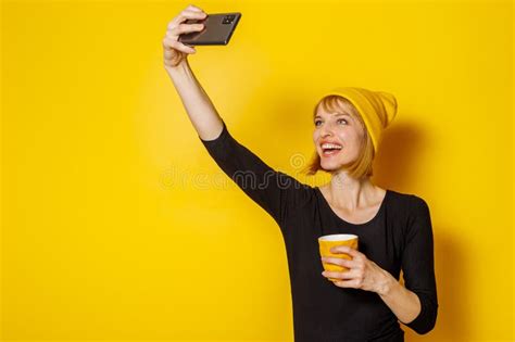 Woman Taking Selfie While Drinking Coffee On Yellow Background Stock
