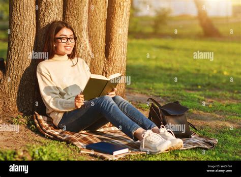 Young Girl Reading Book Under Big Tree In The Park Stock Photo Alamy