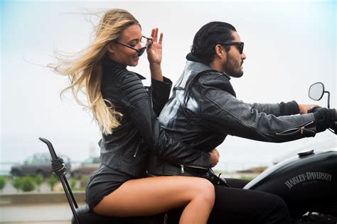Couple Riding A Motorcycle With Leather Jackets Sunglasses And The Wind Blowing Their Hair