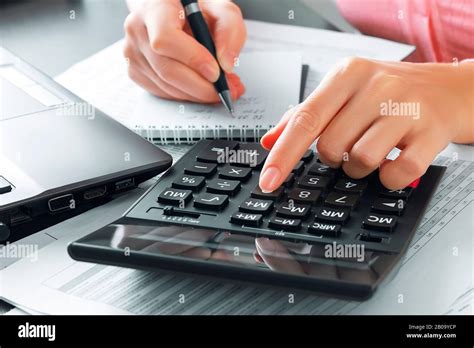 Female Accountant In The Office Uses A Calculator And Writes Data In A