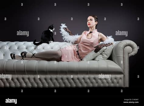 An Elegant Vintage Lady Is Lying On A Sofa With A Kitten Looking At