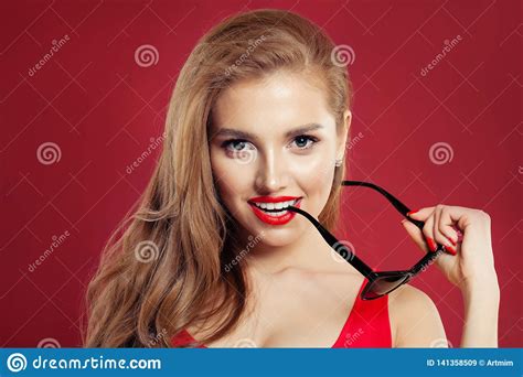 perfect woman with sunglasses and red lips makeup on colorful red background portrait stock