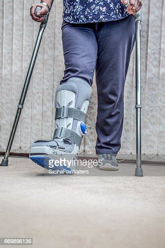 Mature Woman Wearing Leg Brace And Crutches High Res Stock Photo
