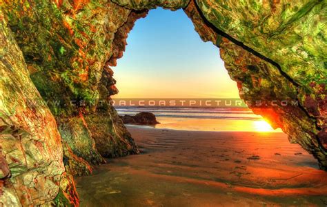 The Sun Is Setting Through An Arch At The Beach