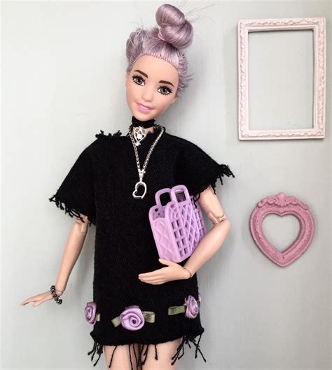 a doll is holding a purse and posing for the camera in front of a wall