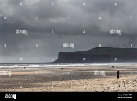 People Walking On The Beach As Storm Clouds Roll Over Saltburn By The