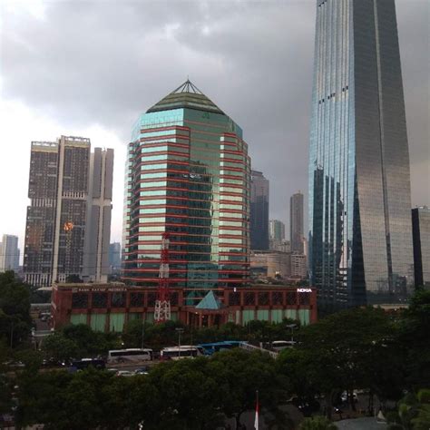 Pemandangan gedung pencakar langit kaca modern yang mencerminkan bangunan di sekitar, gambar berwarna biru. Gambar Pemandangan Gedung - Gambar Kelabu