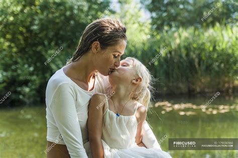 Madre e hija besándose en un lago Relajado Naturaleza Stock Photo