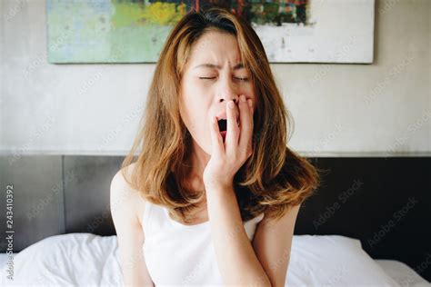 Portrait Of Sleepy Woman Yawing After Her Waking Up In The Early Morning Sitting In Bed With