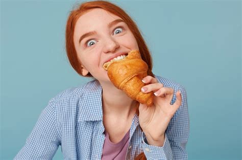 Free Photo Close Up Of Hungry Red Haired Woman Eating Croissant