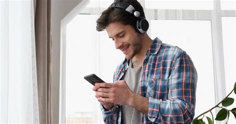 Happy Man Using Mobile Phone While Listening Music On Headphones Stock