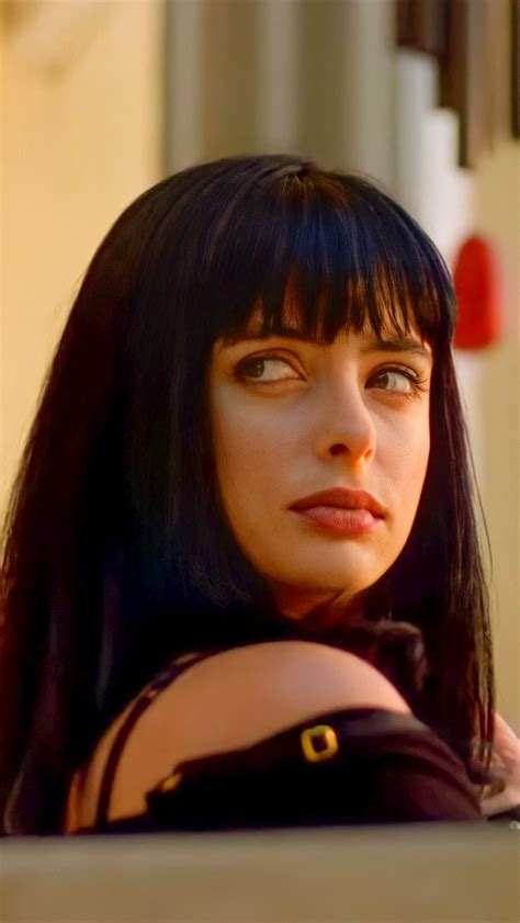 a woman with long black hair and bangs looking at the camera while wearing a dress